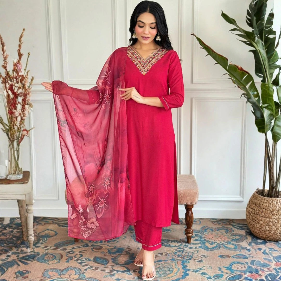 Woman in a red traditional outfit with a matching dupatta in a room with decorative elements.
